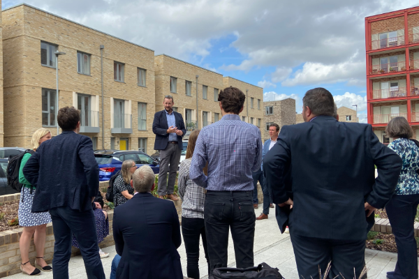 Visitors attending a site tour at Ironworks in Cambridge, standing in a landscaped courtyard between residential apartment buildings during The Housing Forum's Development Partnership Forum.