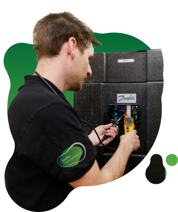 Person adjusting an insulated Danfoss heat interface unit unit using a handheld testing device with cables connected.