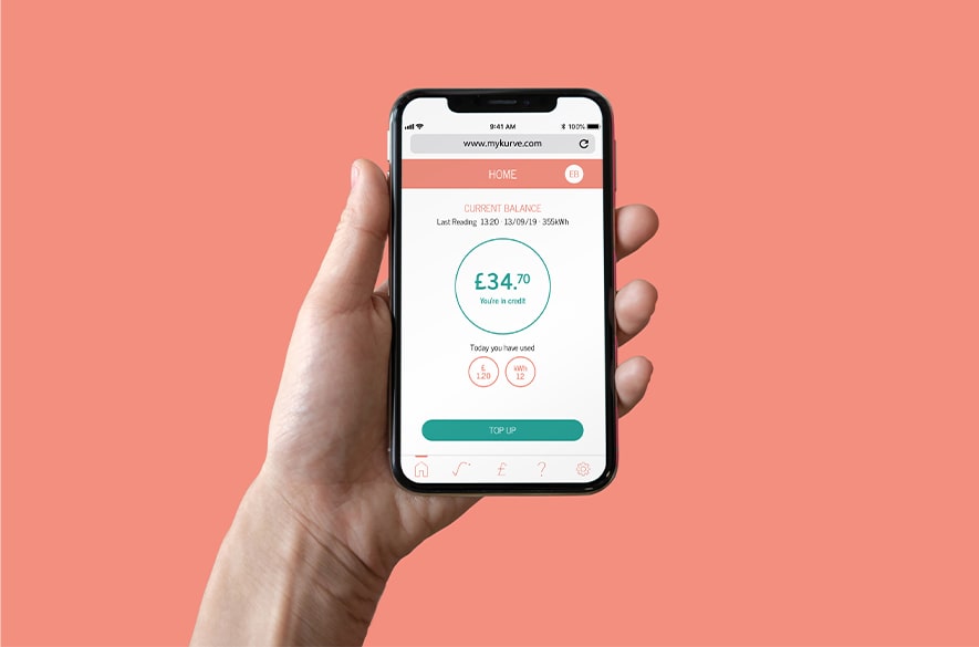 Smartphone held in one hand displaying the KURVE energy account screen, showing a current balance of £34.70 marked as in credit, recent usage indicators, and a “Top up” button on a solid orange background.