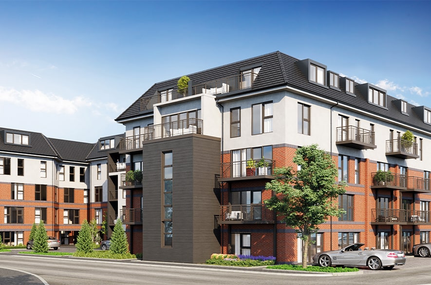 Computer‑generated image of the Greenside Views residential development, showing a mid‑rise apartment building with brick and light‑coloured façades, balconies on multiple levels, and a pitched roof. The building sits alongside a road with parked cars, trees, and landscaped planting under a clear blue sky.