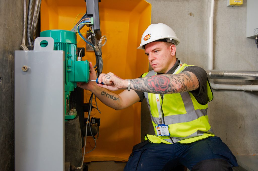 Engineer with Insite branded hard hat checking a heat pump in an energy centre.