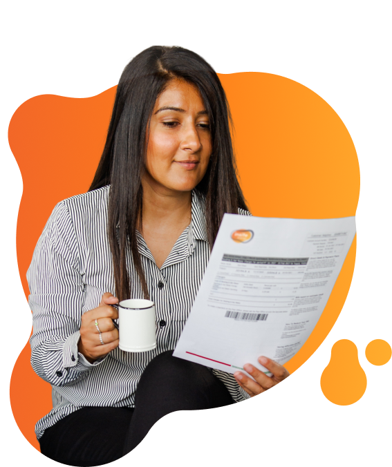 Person seated indoors reading an Insite Energy utility bill while holding a mug, with the document held in the other hand.