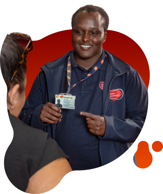 Person holding up a staff ID badge while speaking to another person indoors, with Insite Installations branding visible on their clothing.