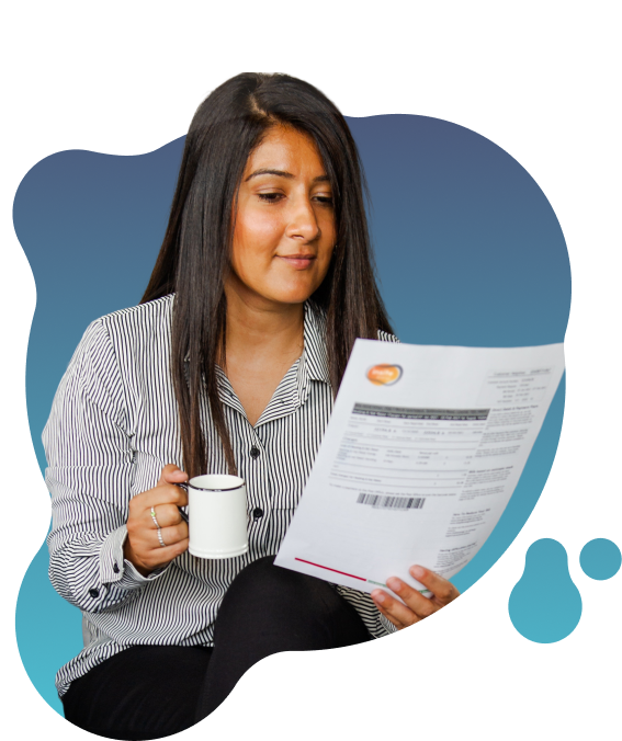 Person seated indoors reading an Insite Energy utility bill while holding a mug, with the document held in the other hand.