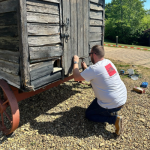 An Insite employee painting the door of a goat enclosure black at Sacrwell Farm.