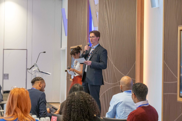 Speaker (Jarrad Bedford of Insite Energy) presenting on a podium during the Insite Partners Summit, addressing attendees in a conference setting.